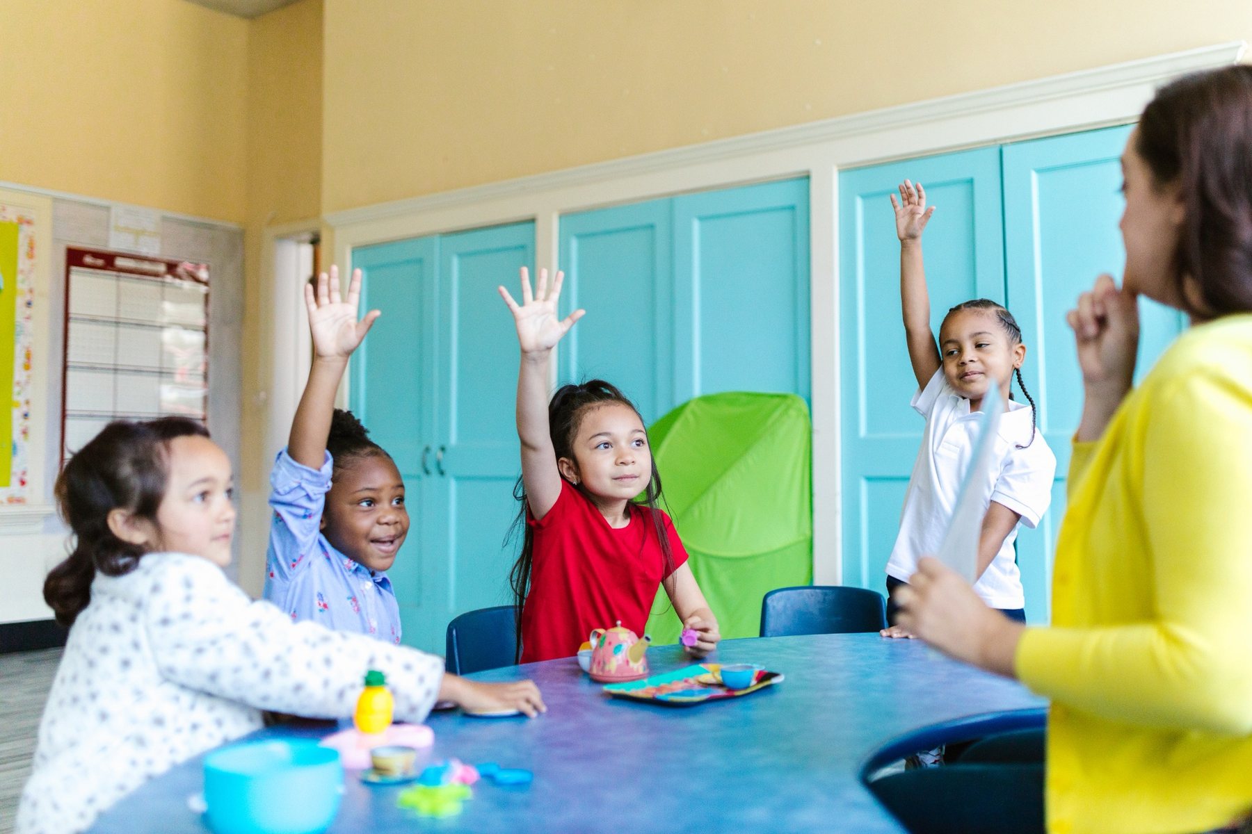 Young students raising their hands during an engaging learning activity