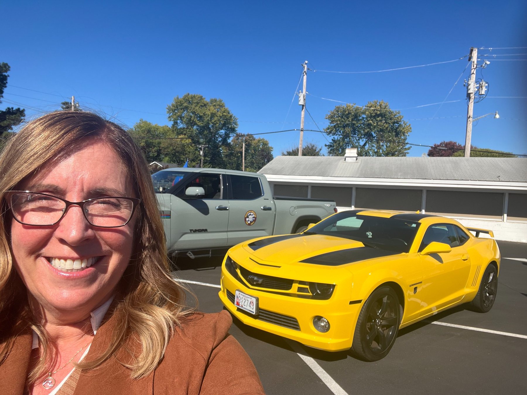 A smiling attendee with a yellow Bumblebee-style Camaro at the Transformers VIP experience